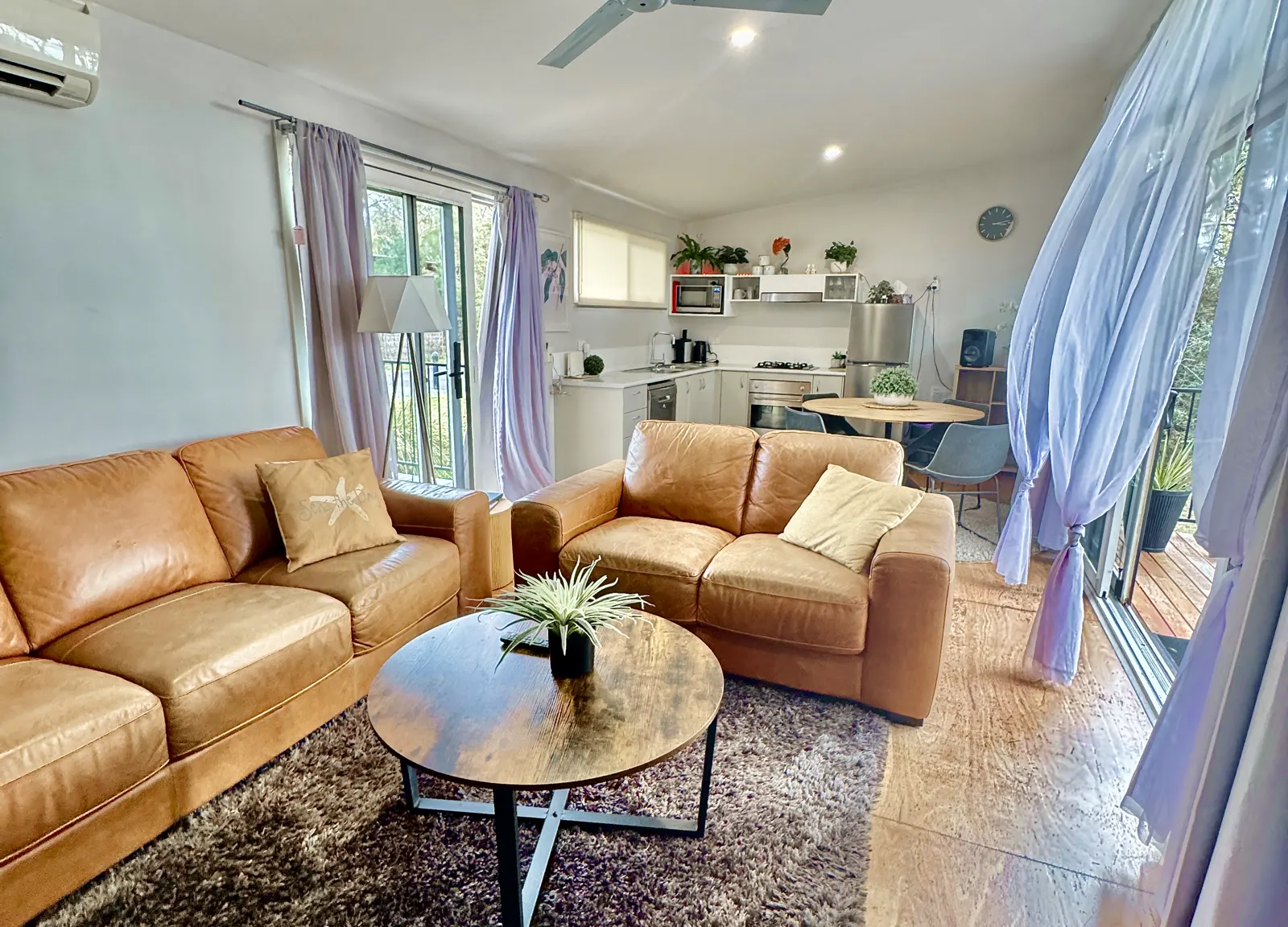 Tan sofas and coffee table in the open-plan living and kitchen area — Two-bedroom Villa 107, Cowes, Phillip Island