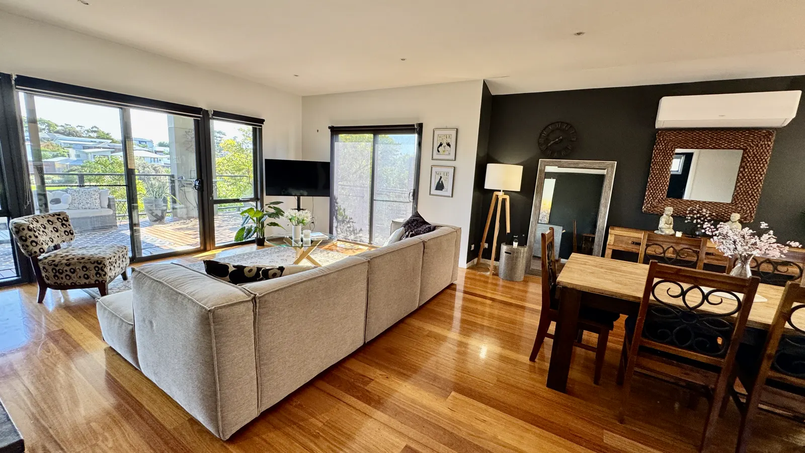 Open-plan living and dining room with a white sofa and timber floors — Coastal Tones holiday home, Cowes, Phillip Island