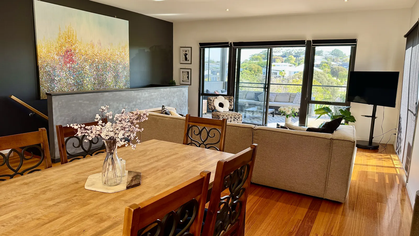 Timber dining table and living area beside large park-facing windows — Coastal Tones holiday home, Cowes, Phillip Island
