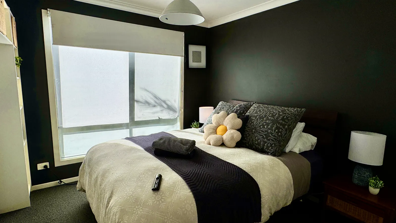 Bedroom with a dark accent wall, flower cushion and large window — Coastal Tones holiday home, Cowes, Phillip Island