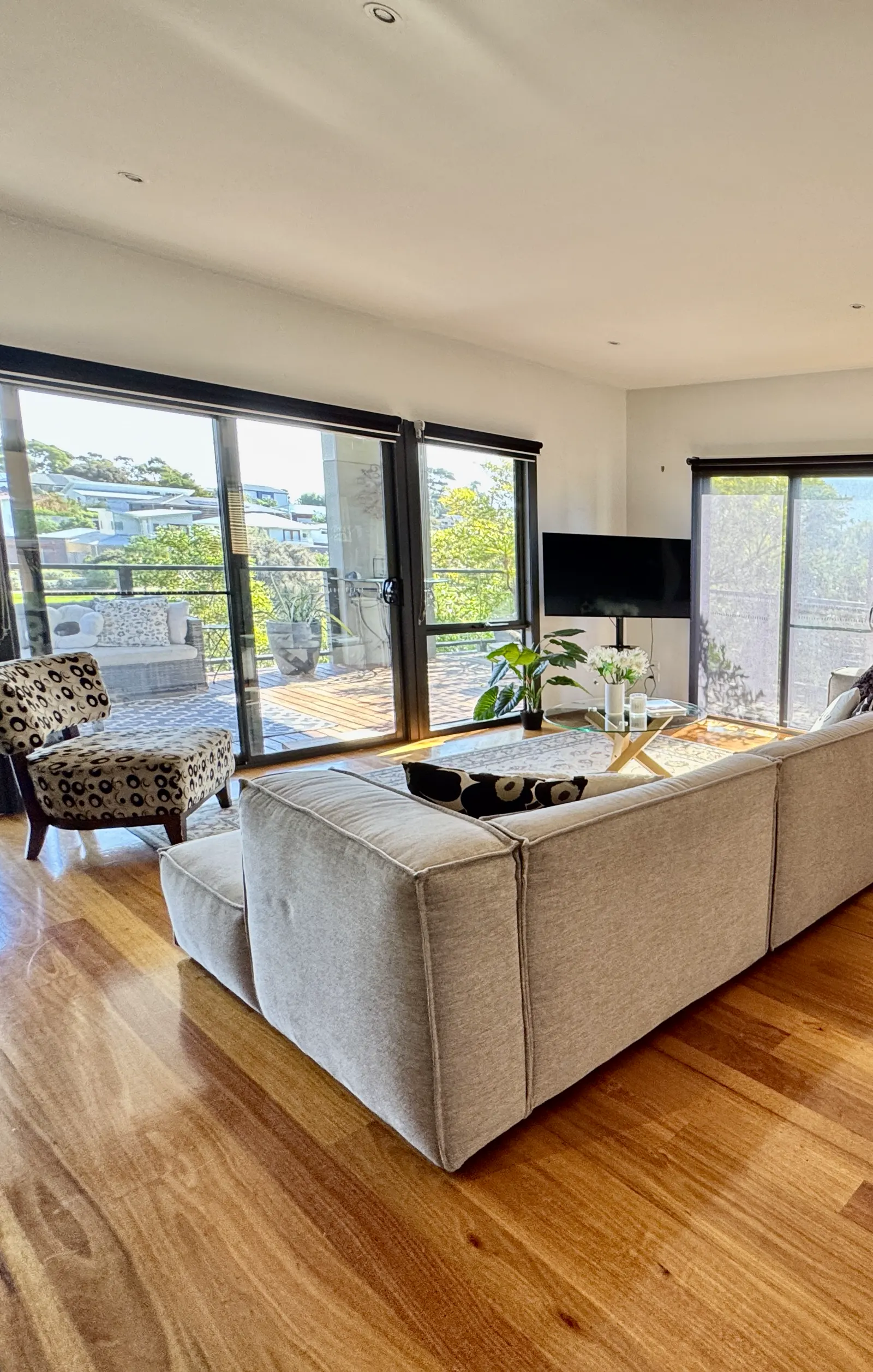 White sofa beside the timber dining area and sunlit windows — Coastal Tones holiday home, Cowes, Phillip Island