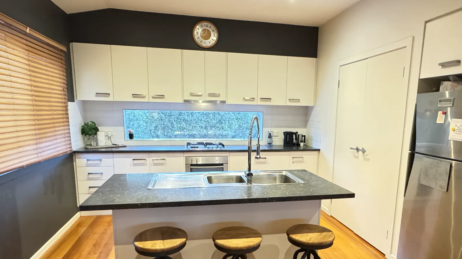 Kitchen with a breakfast bar, stools and large window — Coastal Tones holiday home, Cowes, Phillip Island