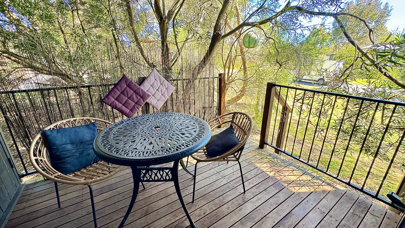 Private deck with a round table for two beneath leafy trees — Studio Spa Villa 127, Cowes, Phillip Island