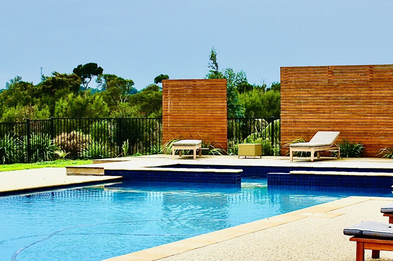 Resort pool beside sun lounges and timber privacy screens