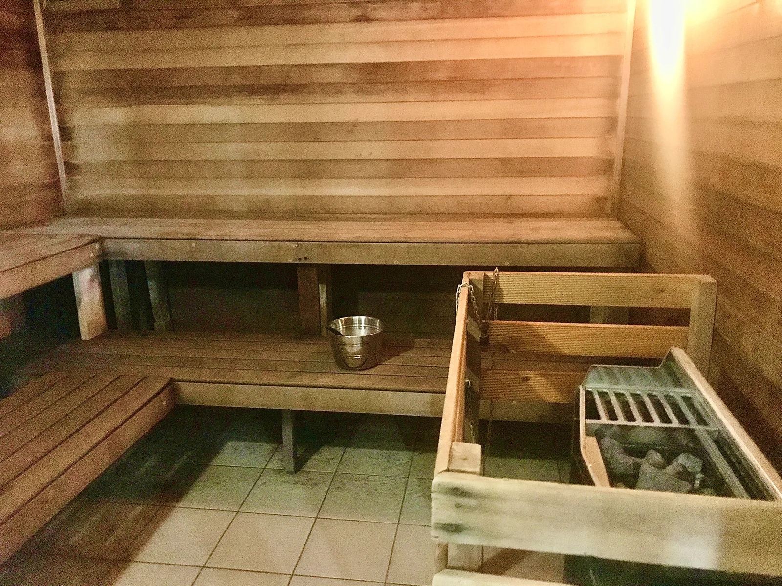Timber benches and a stone heater inside the resort sauna